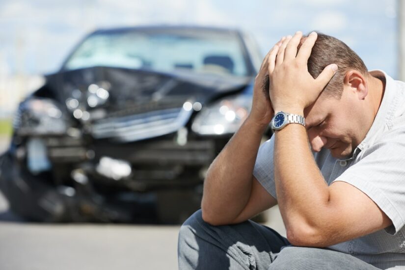 Sad Man Holding His Head In His Arms After A Car Crash