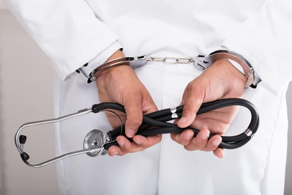 Handcuffed Doctor Holding Stethoscope